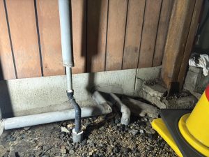 低い位置で新しい配管を接続し直している工程。工具が置かれている。